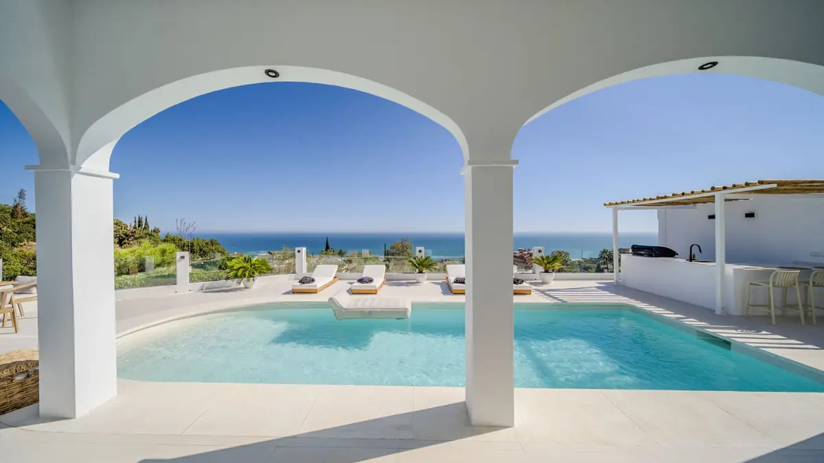 Two white arches framing the pool and the Mediterranean at Villa Zentosa