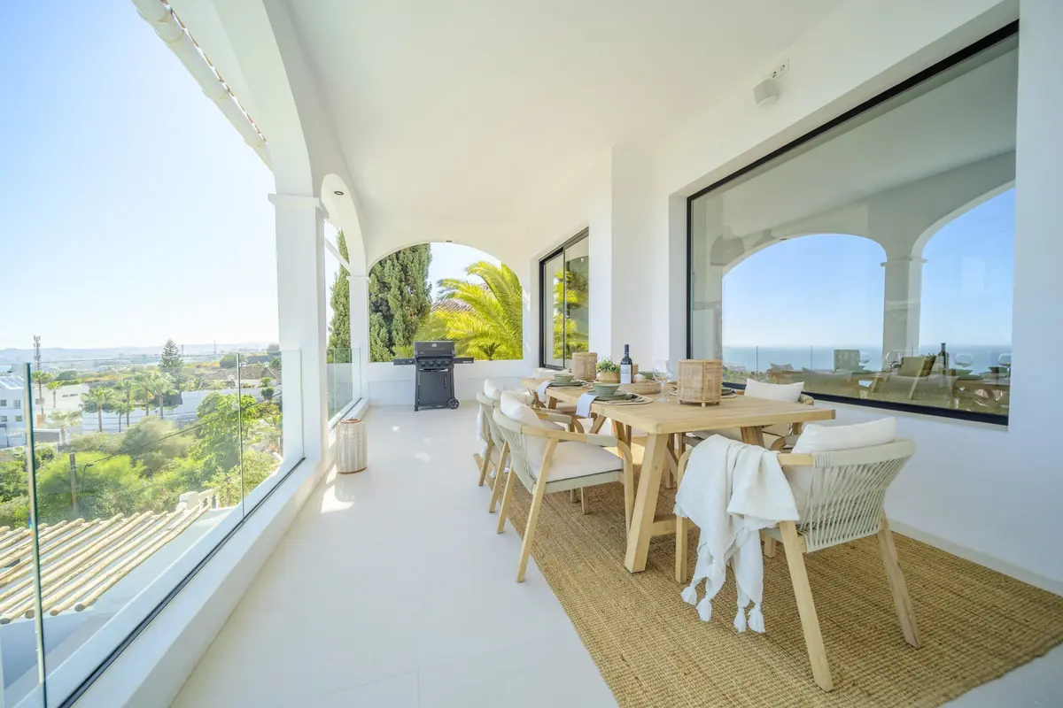 Glazed terrace with a dining table and views at Villa Zentosa